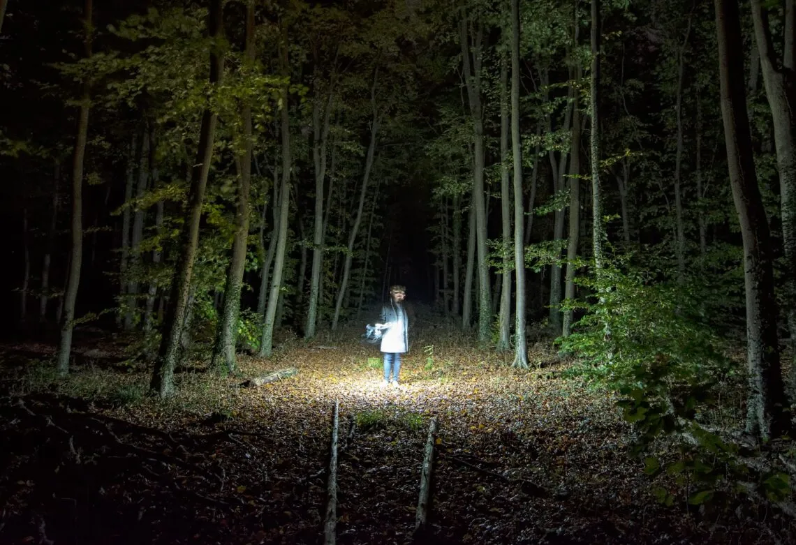 Traileur à la frontale sur un sentier de forêt, de nuit